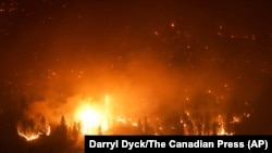 The McDougall Creek wildfire burns on the mountainside above lakefront homes in West Kelowna, Canada, Aug. 18, 2023.