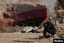 Seorang pria tampak bersedih ketika warga mencari barang-barang pribadi di puing-puing blok apartemen yang runtuh, setelah gempa mematikan, di Kahramanmaras, Turki, 18 Februari 2023. (Foto: Reuters)