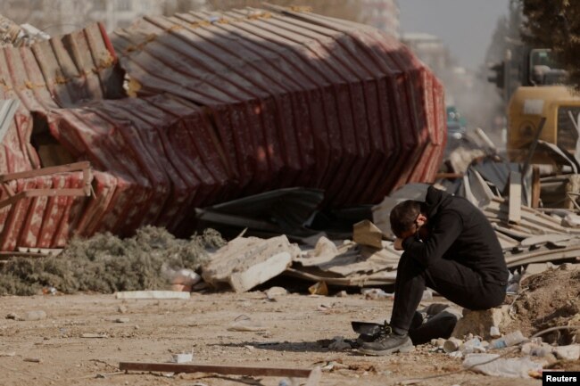 Seorang pria tampak bersedih ketika warga mencari barang-barang pribadi di puing-puing blok apartemen yang runtuh, setelah gempa mematikan, di Kahramanmaras, Turki, 18 Februari 2023. (Foto: Reuters)