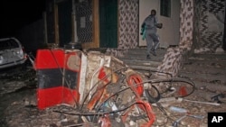 FILE - A man walks past a destroyed vehicle at the scene of a blast at a popular restaurant in the capital Mogadishu, Somalia, March 5, 2021. Police said at least 10 people were killed and more than 30 wounded. 