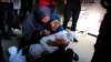 Refah'taki Tel el-Sultan bölgesindeki bir sağlık kliniğinde Filistinli bir kadın İsrail'in bombardımanı sonucu yaşamını yitiren bir bebeğin kefenli cesedini taşıyor