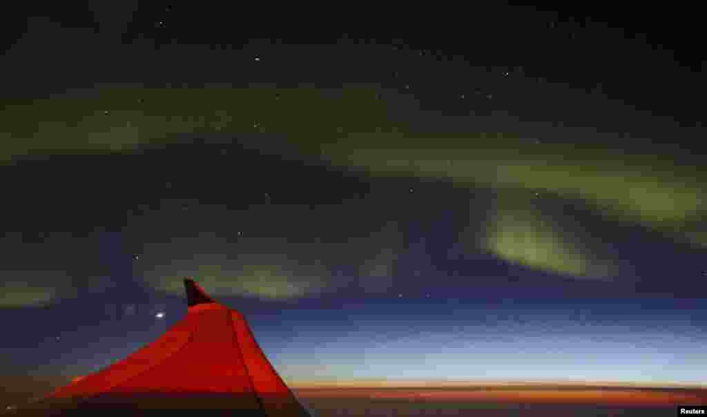 The Aurora Borealis, known as the Northern Lights, illuminates the sky as seen from a passenger plane flying to Europe as it passes the southern coast of Greenland.