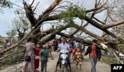 Los residentes caminan junto a los árboles caídos en Kyauktaw, en el estado de Rakhine, en Myanmar, el 15 de mayo de 2023, después de que el ciclón Mocha se estrellara contra la costa.