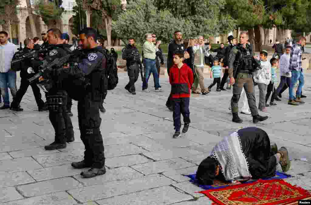 Members of the Israeli security forces stand near Palestinian people praying at the Al-Aqsa compound, also known to Jews as the Temple Mount, in Jerusalem&#39;s Old City.