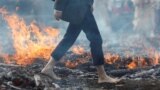 A man walks barefoot across hot embers, remains of a large bonfire of wood and Japanese cypress leaves, at the fire-walking festival at Mt.Takao in Tokyo, March 12, 2023. 