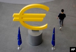 FILE - Seorang pria berjalan melewati tanda Euro di lorong Bank Sentral Eropa (ECB) di Frankfurt, Jerman, 6 Juni 2024. (Michael Probst/AP)