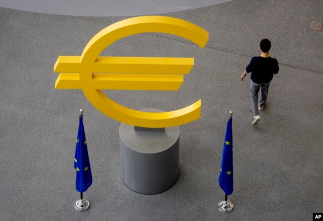 FILE - Seorang pria berjalan melewati tanda Euro di lorong Bank Sentral Eropa (ECB) di Frankfurt, Jerman, 6 Juni 2024. (Michael Probst/AP)