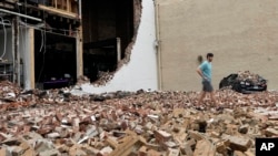 A man walks through fallen bricks from a damaged building in the aftermath of a severe thunderstorm May 17, 2024, in Houston. 