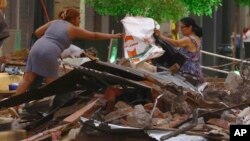 Residents recover belongings from the debris of their collapsed homes after an earthquake shook Machala, Ecuador, March 18, 2023.