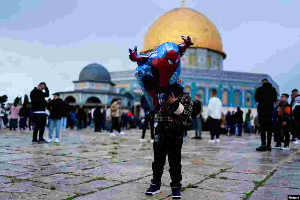 A child holds a balloon as Muslims gather at Al-Aqsa compound, also known to Jews as Temple Mount, on Eid al-Fitr, which marks the end of Ramadan, in Jerusalem&#39;s Old City.