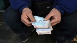 Seorang pedagang valuta jalanan sedang menghitung uang kertas Iran di Teheran, Iran, 23 Desember 2022. (Foto: Vahid Salemi/AP Photo)