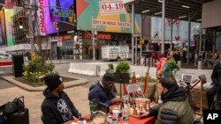 Tunde Onakoya, center, a Nigerian chess champion and child education advocate, plays a chess game in Times Square, Friday, April 19, 2024, in New York.