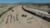 Migrants wait for U.S. authorities between a barbed-wire barrier and the border fence at the US-Mexico border, as seen from Ciudad Juarez, Mexico, May 9, 2023. 