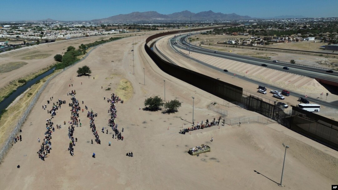 Migrants wait for U.S. authorities between a barbed-wire barrier and the border fence at the US-Mexico border, as seen from Ciudad Juarez, Mexico, May 9, 2023. 