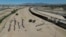 Migrants wait for U.S. authorities between a barbed-wire barrier and the border fence at the US-Mexico border, as seen from Ciudad Juarez, Mexico, May 9, 2023. 