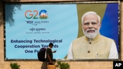 一名印度工人走過新德里街頭樹立的G20峰會宣傳畫。（2023年9月4日）