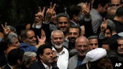 Lide politik Hamas Palestinyen an Ismail Haniyeh (mitan) fe siy viktwa a pandan li antoure pa yon gwoup palmante Iranyen apre fen seremoni envestiti nouvo prezidan eli Iranyen an, Massoud Pezeshkian, nan palman an nan Teheran, 30 Jiye, 2024. 