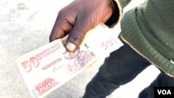 A man in Harare holds a Zimbabwe dollar, April 4, 2024, which is worth less than a cent. Most traders are refusing to accept it. (Columbus Mavhunga/VOA) 