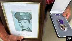 Wilfred Ikemoto holds a photo of his older brother, Haruyuki Ikemoto, and the Purple Heart medal posthumously awarded to him, in Pearl Harbor, Hawaii, on May 10, 2024.
