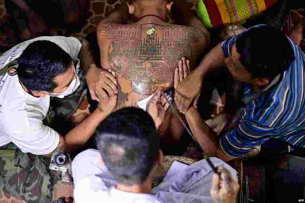 A Buddhist devotee (C) gets a traditional &quot;Sak Yant&quot; tattoo during an annual sacred tattoo festival at the Wat Bang Phra temple in Nakhon Pathom province,&nbsp; Thailand, March 4, 2023.