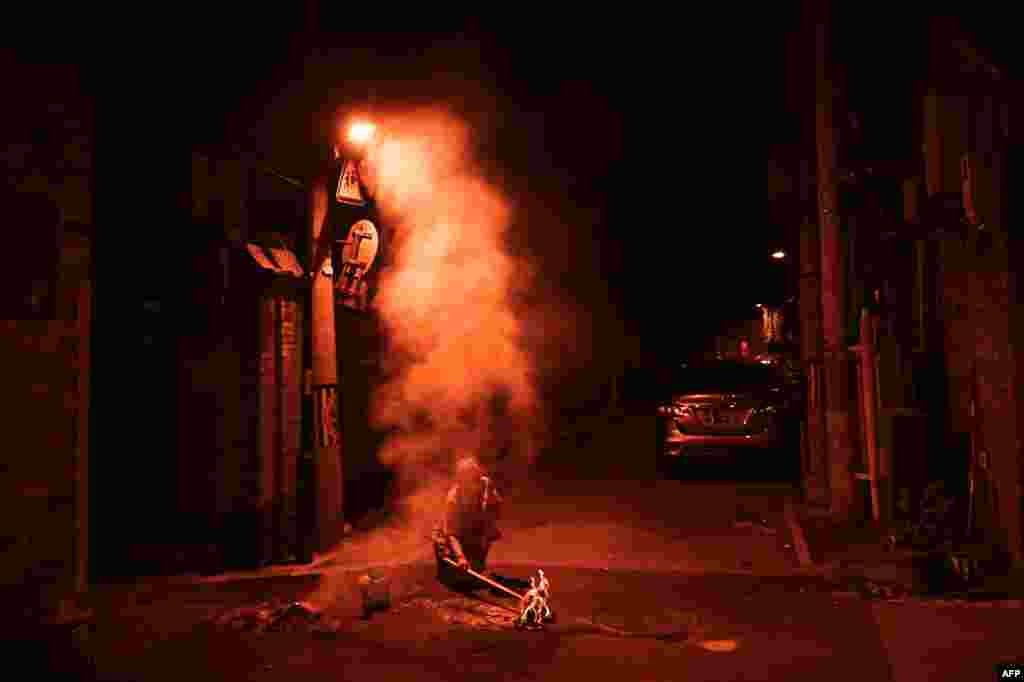 Seorang wanita membakar persembahan (sesaji) di jalan untuk leluhurnya yang telah meninggal selama Festival &quot;Hantu Kelaparan&quot; di Beijing, China. (AFP)&nbsp;