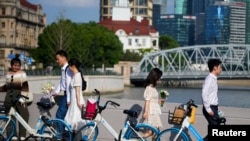 FILE - Couples prepare to get their photo taken during a wedding photography shoot on a street, in Shanghai, China Sept. 6, 2023.