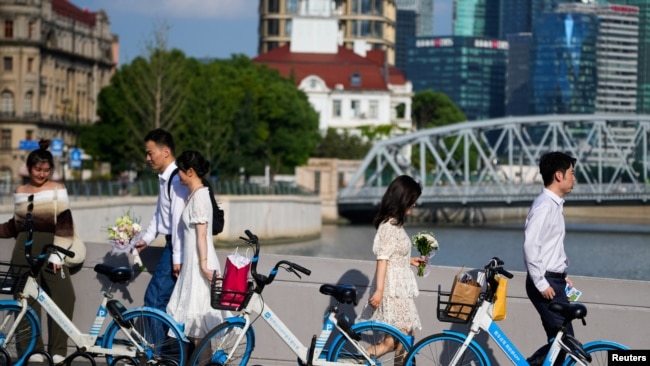 FILE - Couples prepare to get their photo taken during a wedding photography shoot on a street, in Shanghai, China Sept. 6, 2023.