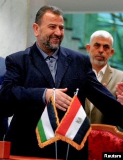 Head of Hamas delegation Saleh al-Arouri, with Gaza's Hamas leader Yahya Sinwar behind him, signs a reconciliation deal with Fatah leader Azzam Ahmad (not pictured), in Cairo, Egypt, Oct. 12, 2017.