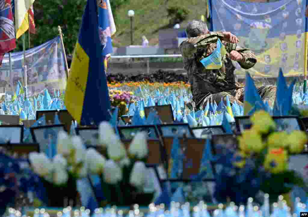 A Ukrainian serviceman reacts as he sets a flag in a makeshift memorial for fallen Ukrainian soldiers at the Independence Square in Kyiv, amid the Russian invasion in Ukraine.