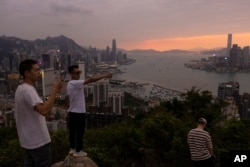 Mainland Chinese tourists look at sunset from a hill in Hong Kong, April 26, 2023.