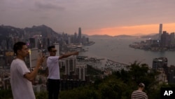 中国大陆游客在山顶拍摄香港夕照景色。(2023年4月26日)