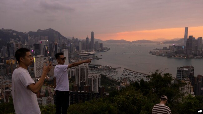 中国大陆游客在山顶拍摄香港夕照景色。(2023年4月26日)