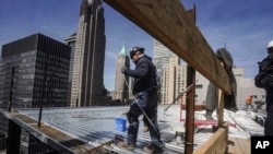 资料照片：2023年4月11日，建筑工人在纽约曼哈顿金融区的一座高层建筑上安装屋顶。（美联社照片）
