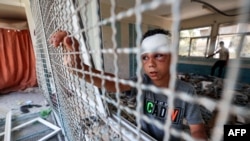 FILE - An injured boy stands by a window lattice in a destroyed classroom where people were sheltering at a school run by the U.N. Relief and Works Agency for Palestine Refugees that was previously hit by Israeli bombardment, in the Nuseirat camp in the Gaza Strip, June 7, 2024.