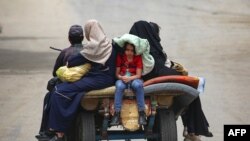 Palestinians sit on an animal pulled cart as they move to safer areas in Rafah, in the southern Gaza Strip, amid the ongoing conflict between Israel and the militant group Hamas.