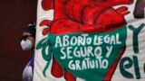 FILE - A woman holds a banner reading in Spanish, 'Legal, safe, and free abortion' as abortion rights protesters demonstrate in Mexico City, Sept. 28, 2020.