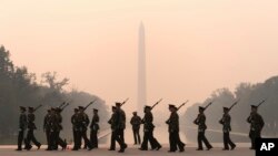 With the Washington Monument in the background and a thick layer of smoke, Marine Corps honor color guard rehearse, June 8, 2023, in Washington.