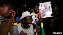 Supporters of Senegalese presidential candidate Bassirou Diomaye Faye celebrate early results showing that Faye is leading initial presidential election tallies, in Dakar, Senegal, March 24, 2024. 