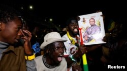 Supporters of Senegalese presidential candidate Bassirou Diomaye Faye celebrate early results showing that Faye is leading initial presidential election tallies, in Dakar, Senegal, March 24, 2024. 