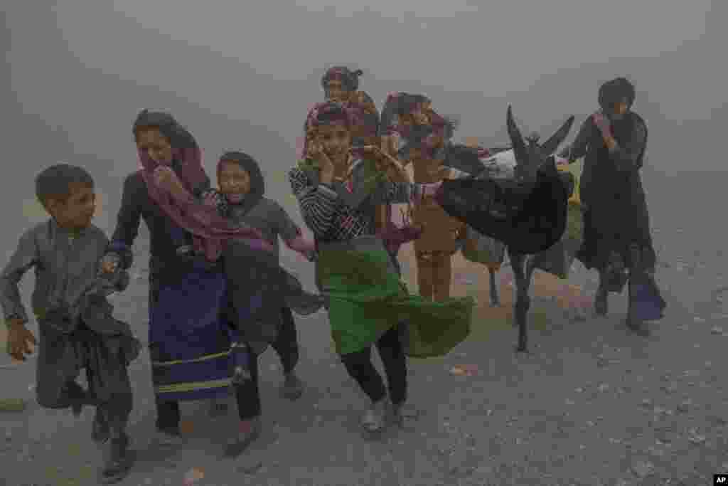 Girls and women carry donated aid to their tents during the fierce sandstorm after an earthquake in Zenda Jan district in Herat province, western of Afghanistan, Oct. 12, 2023.