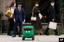 Robot pengantar makanan Uber Eats menunggu untuk menyeberang jalan saat demonstrasi untuk media di Tokyo, Jepang, Selasa, 5 Maret 2024. (AP/Shuji Kajiyama)