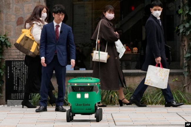 Robot pengantar makanan Uber Eats menunggu untuk menyeberang jalan saat demonstrasi untuk media di Tokyo, Jepang, Selasa, 5 Maret 2024. (AP/Shuji Kajiyama)