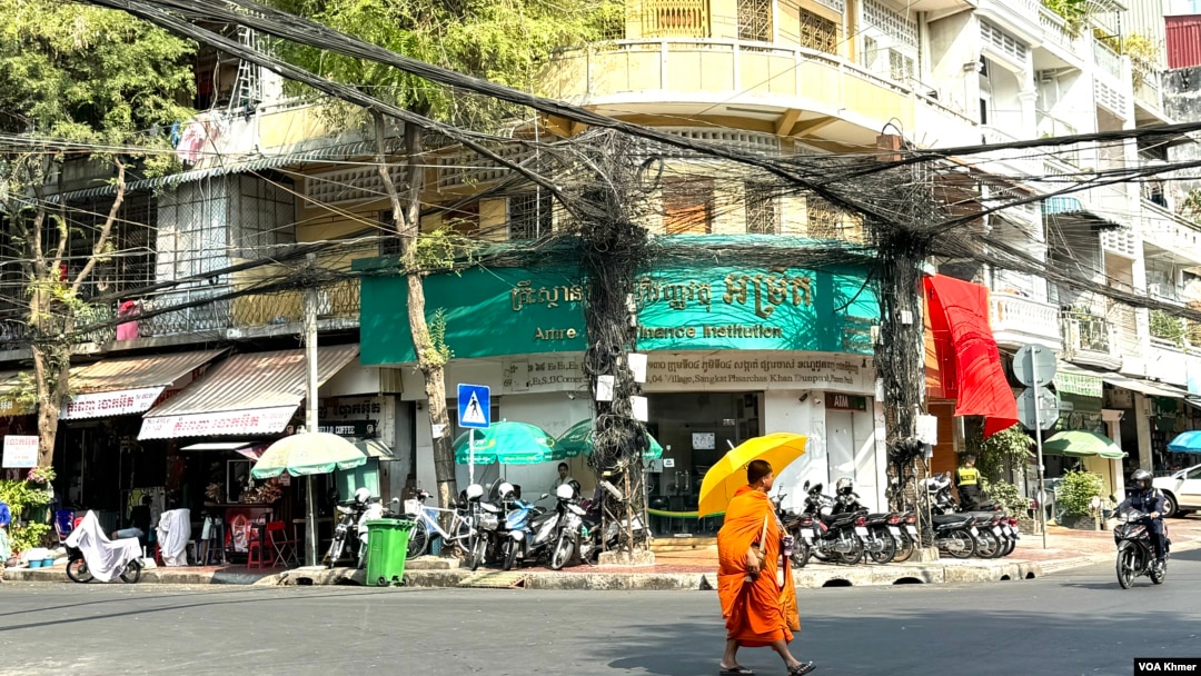 A monk walks in front of a branch office of Amret Microfinance Institution in Daun Penh district, Phnom Penh, Cambodia’s capital, April 5, 2024. (Sun Narin/VOA Khmer)