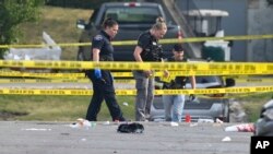 Investigators look over the scene of an overnight mass shooting at a strip mall in Willowbrook, Illinois, June 18, 2023.