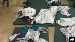 FILE - In this photo provided by US Customs and Border Protection, people who've been taken into custody related to cases of illegal entry into the US rest in one of the cages at a facility in McAllen, Texas,, June 17, 2018
