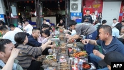 中国山东淄博五一节期间民众在烧烤摊旁品尝烧烤。(2023年5月2日)