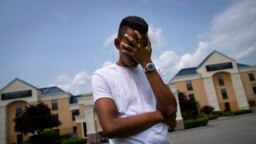 Mohamed, 19-godišnji mladić koji bježi od političkog progona u Mauritaniji, zaklanja lice kako bi zaštitio svoj identitet, ispred hotela Crossroads, prije nego što se uputio u grad radi mogućnosti za posao, 22. maj 2023., u Newburghu, N.Y. 