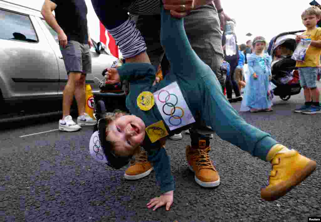 Brodie White, 1, dressed as the Australian Olympic breakdancer Rachael Gunn, is held by his dad at a children's fancy dress parade at the Cruinniu na mBad (gathering of the boats) regatta in Kinvara, Ireland, Aug. 18, 2024.