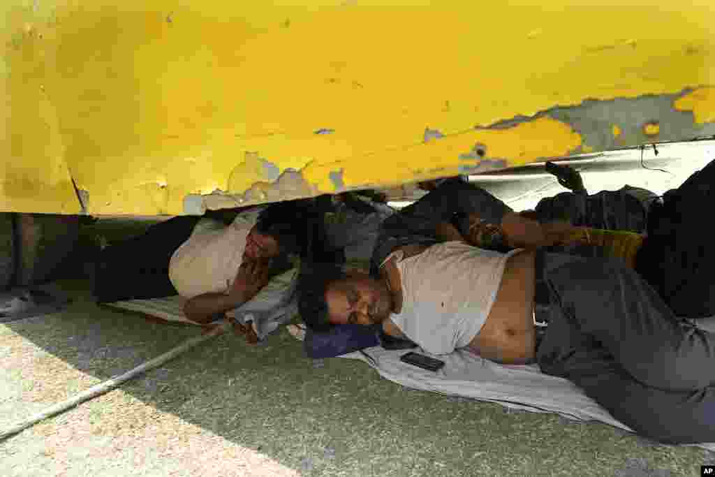 People rest beneath a parked bus on a hot summer day in Prayagraj, Uttar Pradesh, India. Parts of northwest India are sweltering under scorching temperatures with the capital New Delhi under a severe weather alert as extreme temperatures strike parts of the country.