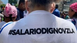 Una trabajadora muestra un eslogan por mejores condiciones laborales grabado en su camiseta, durante una protesta celebrada el 1 de mayo de 2024 en Caracas.
